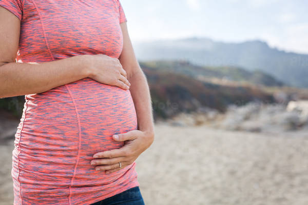 Close-Up of a Pregnant Woman Standing on a Beach and Holding Her Belly