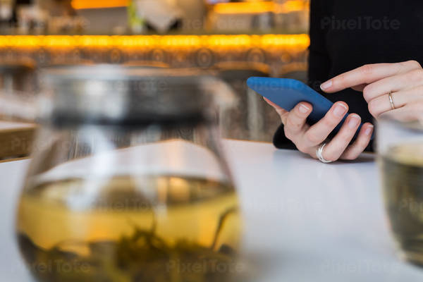 Close-Up View of Hands of a Woman Using a Smartphone in a Cafe