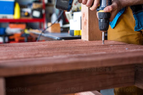 Handyman Using an Electric Screwdriver to Screw Bolts in a Workshop