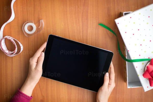 Overhead View of a Woman Holding a Tablet When Wrapping Holiday Presents