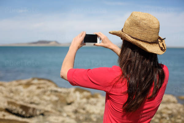 Girl in a Straw Hat Taking a Picture with Her Phone at a Travel Destination