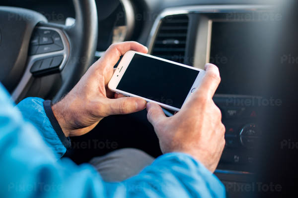 Man Holding a White Cell Phone Inside a Car