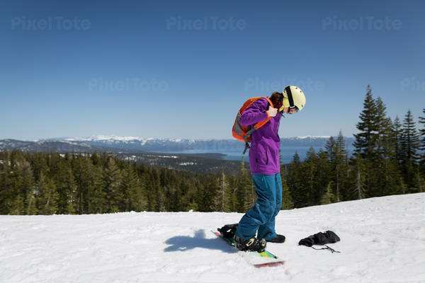 Female Snowboarder with a Backpack on a Top of a Ski Run