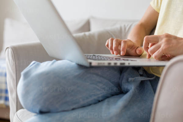 Detailed View of a Young Woman in Casual Clothing Working on a Laptop from Home