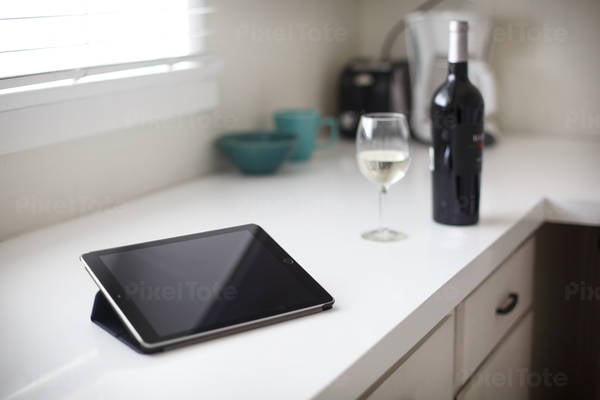 Digital Tablet on a Kitchen Counter with a Wine Glass and a Bottle