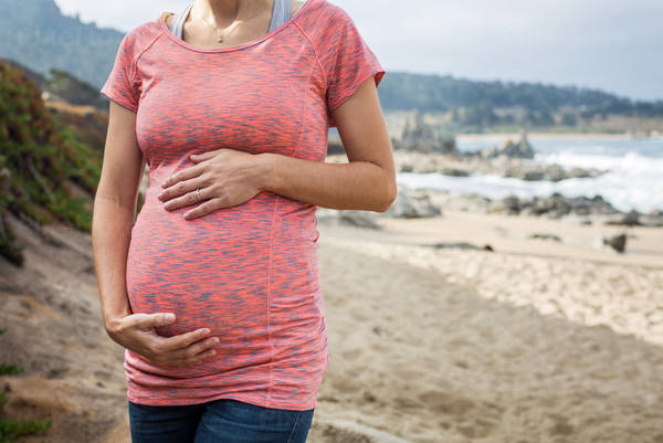 Pregnant Woman Posing on a Beach and Holding Her Belly