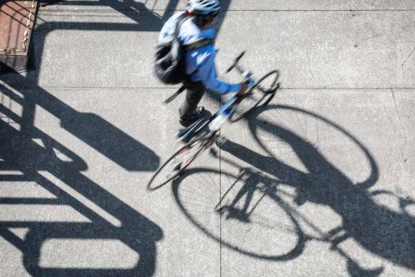 Overhead View of a Businessman Pushing a Bike Casting a Long Shadow