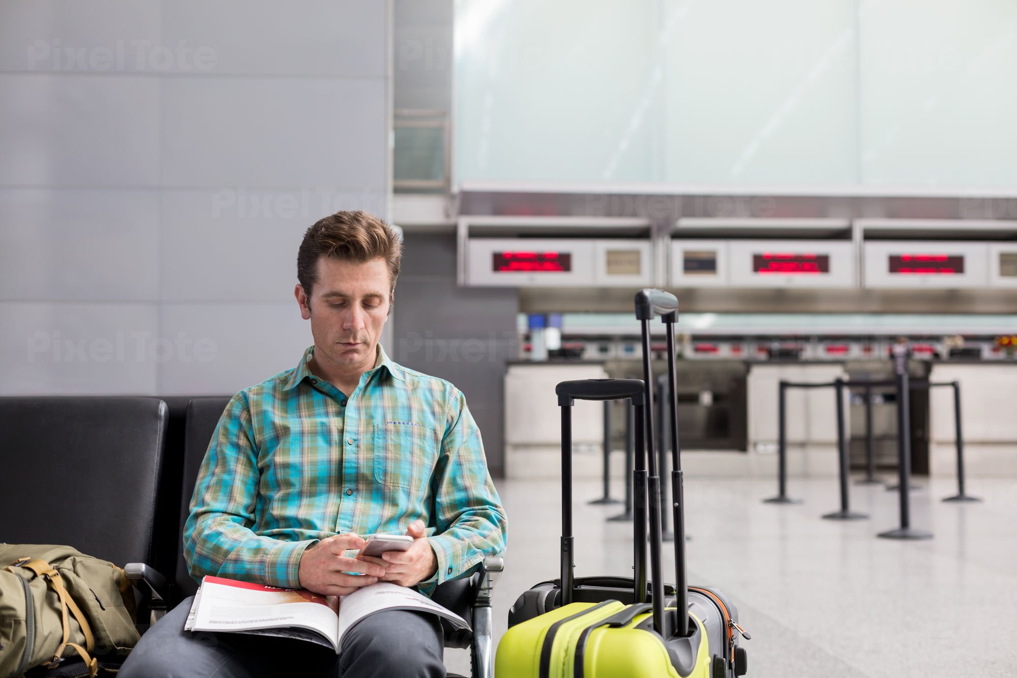 Traveler Sitting at an Airport Stock Photo - PixelTote