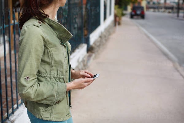Woman Waiting on a Street Holding a Cell Phone