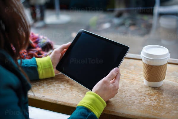 Woman Sitting in a Cafe Holding a Digital Tablet