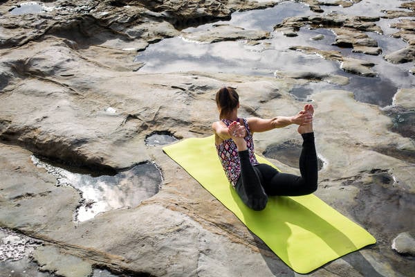 Young Woman Practicing Yoga Bow Pose by Tidal Pools