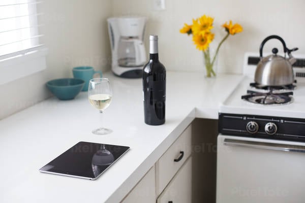 Digital Tablet on a Kitchen Counter with a Wine Glass and a Bottle
