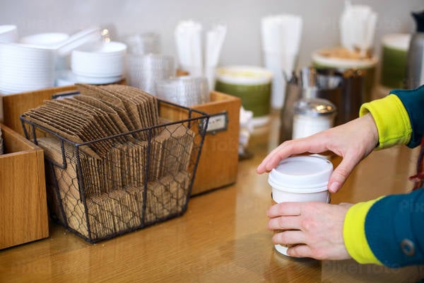 Woman Adding Condiments to Her Coffee at a Contemporary Coffee Shop