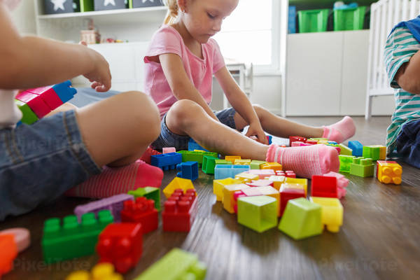Low-Angle View of Children Playing with Plastic Blocks on a Floor