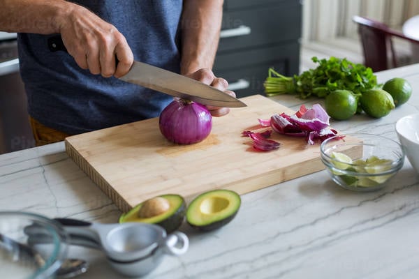  Man Cutting an Onion on a Wooden Board in a Kitchen