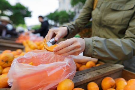 Woman Trying an Orange Sample at a Farmers Market