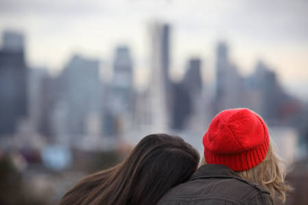 A Girl Leaning on Other Girl's Shoulder in a Park with a View of the City