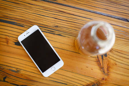 Directly from Above View of a Cell Phone and a Glass Bottle on a Table