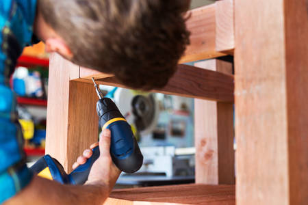Handyman Using an Electric Screwdriver to Assemble a Wooden Planter