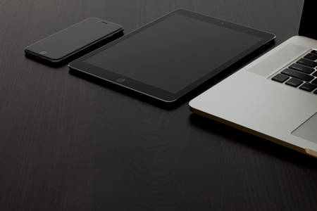 View of a Tablet, Cell Phone and a Laptop on a Black Table