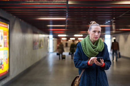 Woman Checking Her Phone in an Underpass During Morning Commute