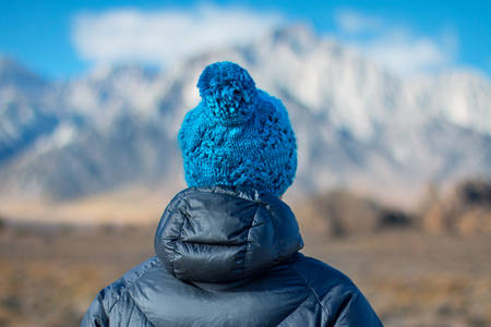 Woman in a Blue Knitted Beanie Looking at Distant Mountains