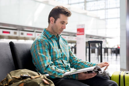 Man Reading a Magazine While Waiting in an Airport Lobby