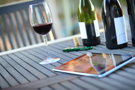 View of a Tablet with Bottles of Wine Next to a Glass and a Bottle Opener