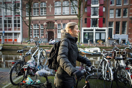 Woman Walking a Bicycle by a Canal in Amsterdam