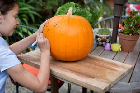 Young Girl Drawing on a Pumpkin Before Carving It