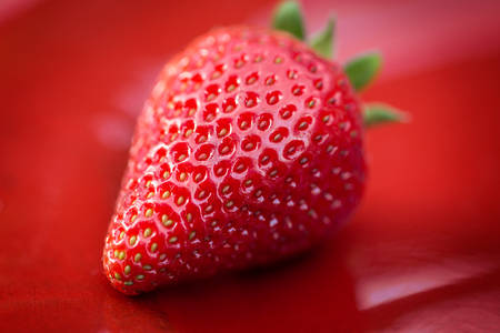 Close-Up View of a Ripe Fresh Strawberry on Red Background