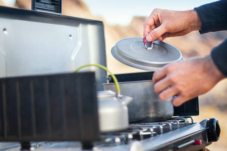 Detailed View of a Man Cooking Meal on a Camping Stove