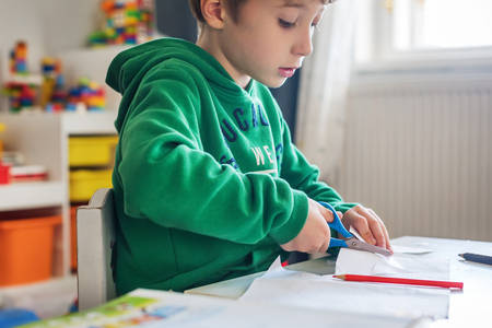 Young Boy Cutting Paper with Scissors at Home