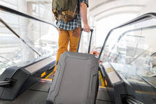 Traveler with a Luggage Walking on to an Escalator at an Airport Lobby