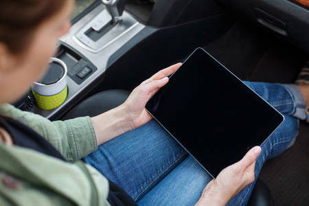 Woman Sitting in a Car Working on a Digital Tablet