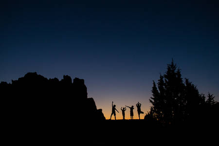 Silhouettes of Children Standing Next a Rock with a Dusk Sky in the Background