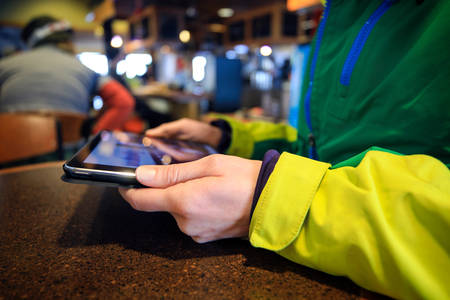 Woman in a Winter Jacket Holding a Tablet Inside an Establishment