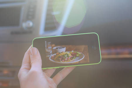 Woman's Hand Holding a Cell Phone in a Car with a Picture of Food