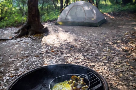 An Iron Skillet with Eggs and Potatoes on a Fire Pit Outdoors 