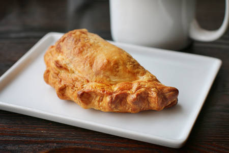 Pastry on a White Plate with a Ceramic Cup in the Background