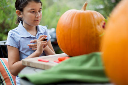 Young Girl Drawing on a Pumpkin During Halloween