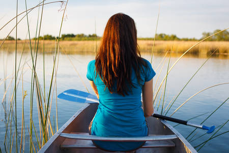 Girl Holding a Paddle Sitting on a Canoe on a Lake