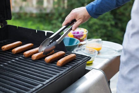 Man Grilling Sausages on a Barbecue in a Garden
