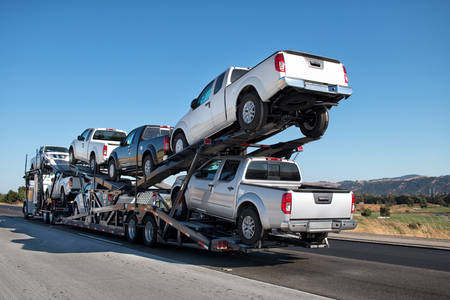 White Pickup Trucks Being Transported on a Trailer Through Highway