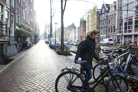 Woman Parking a Bicycle by a Canal in Amsterdam