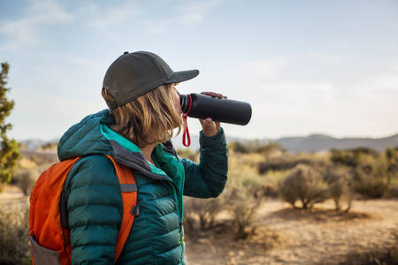 Outdoorsy Woman in a Down Jacket Drinking Water from a Bottle
