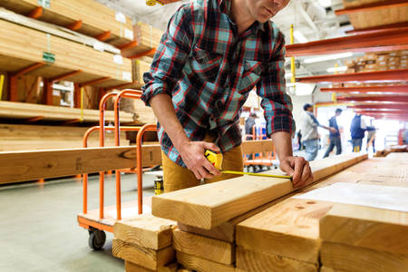 Man Measuring a Wood Board in a Hardware Store