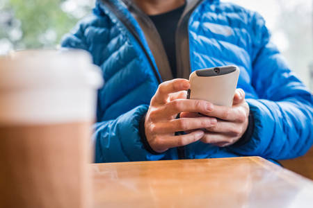 Table-Level Shot of a Man Looking at His Phone at a Coffee Place