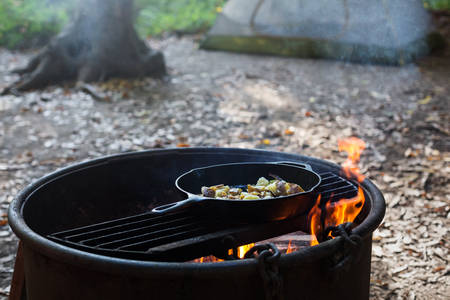 An Iron Skillet with Potatoes Cooking on an Outdoor Campfire 