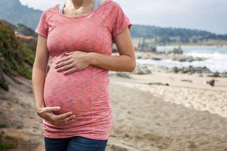 Pregnant Woman Posing on a Beach and Holding Her Belly
